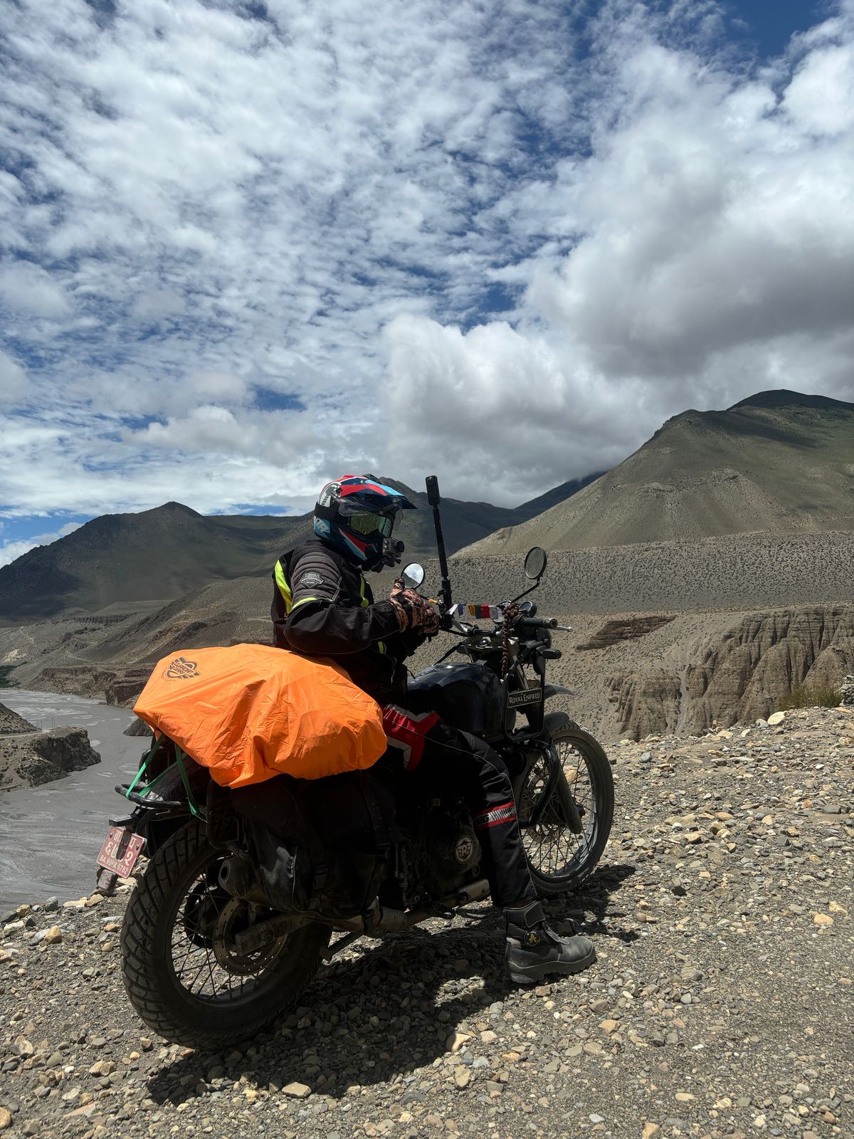 Man on motorbike admiring rugged cliffs in Mustang